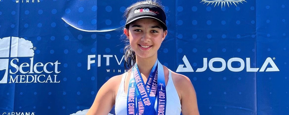 Ella Cosma standing on a podium with three gold medals around her neck
