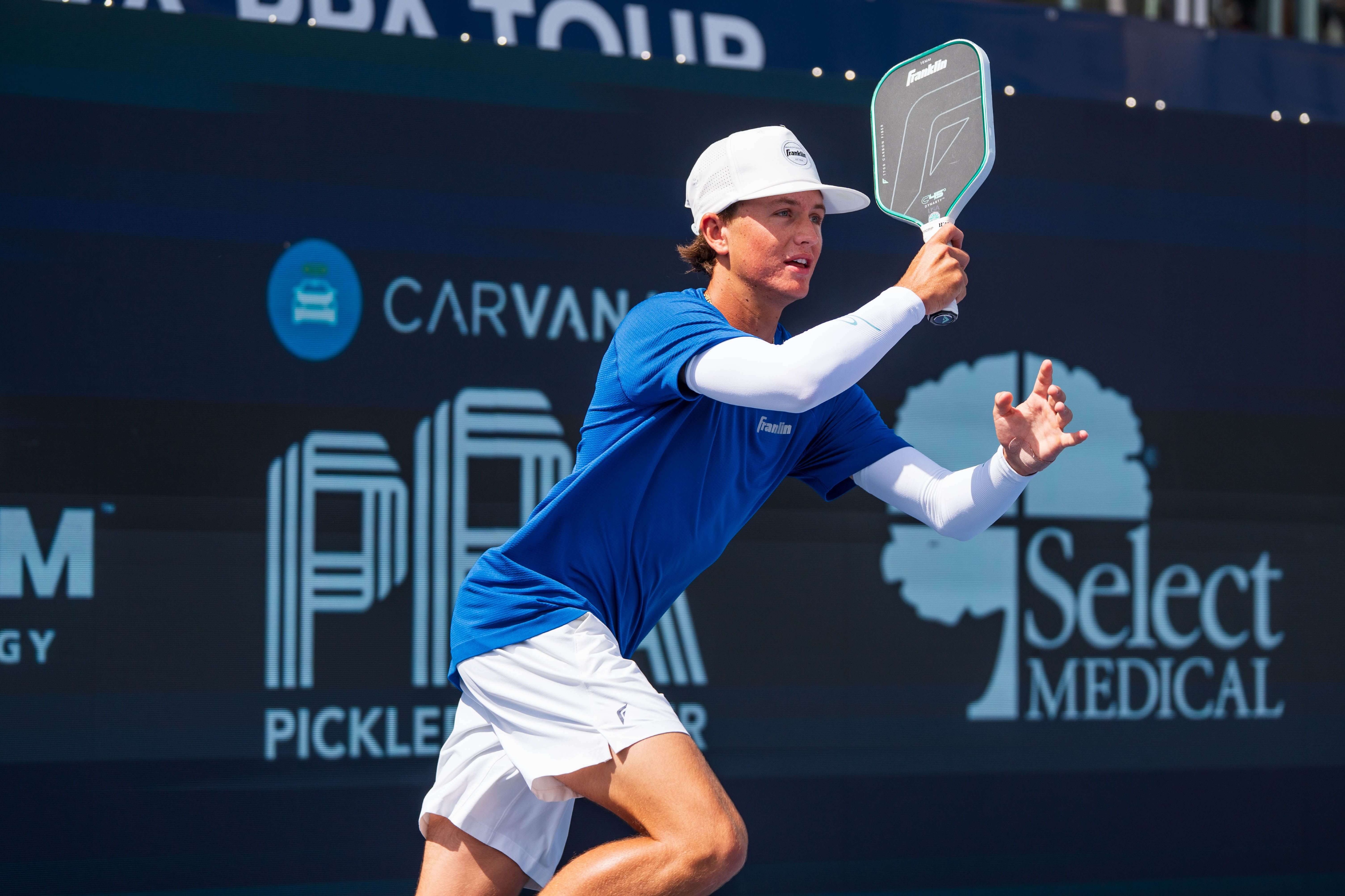 Patriquin in a blue shirt with white shorts, white arm sleeves, and white hat