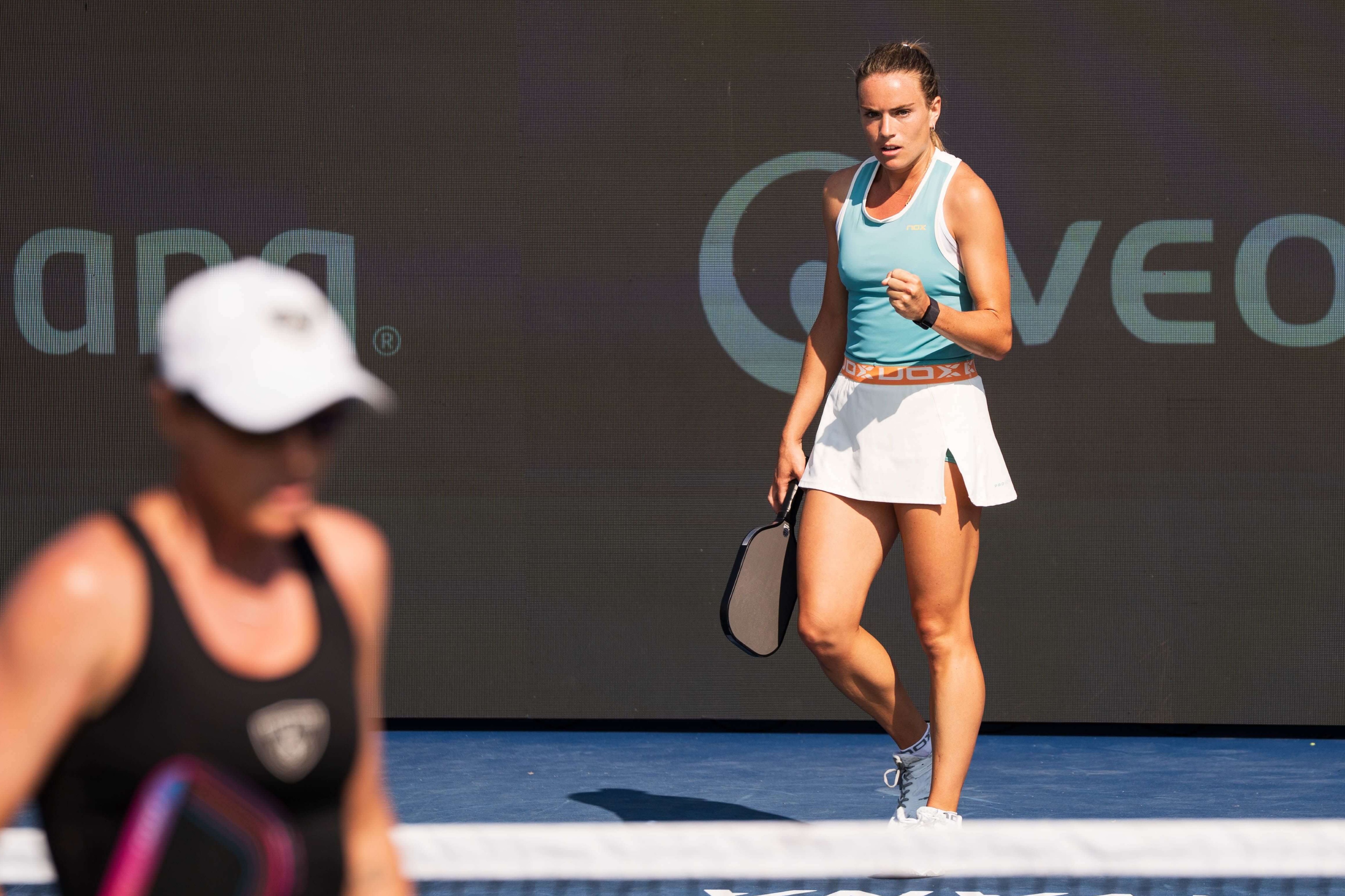 Judit in light blue tank top, white skirt with a orange waist band