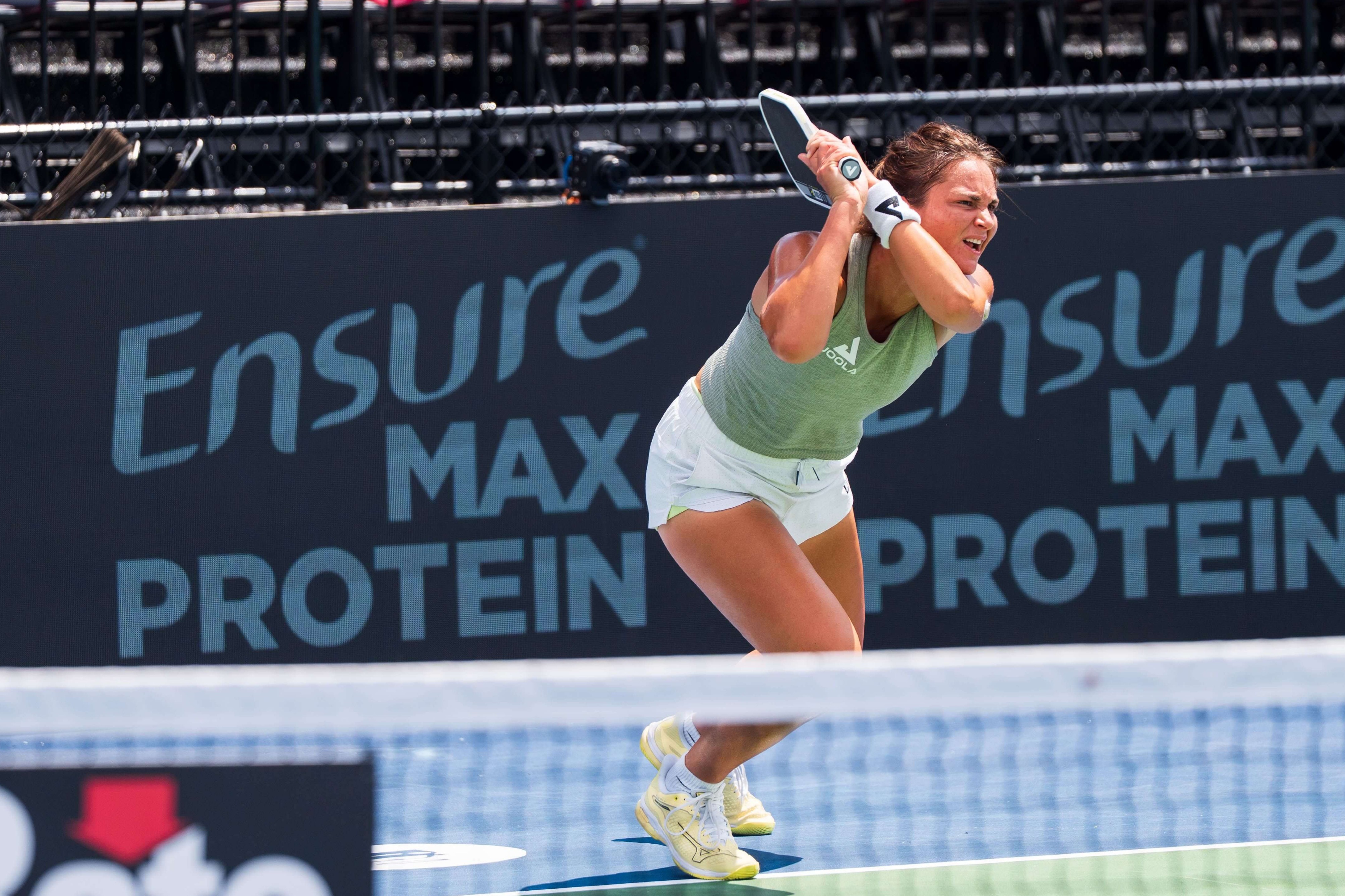 Jansen wearing a light green tank, white shorts, and yellow shoes