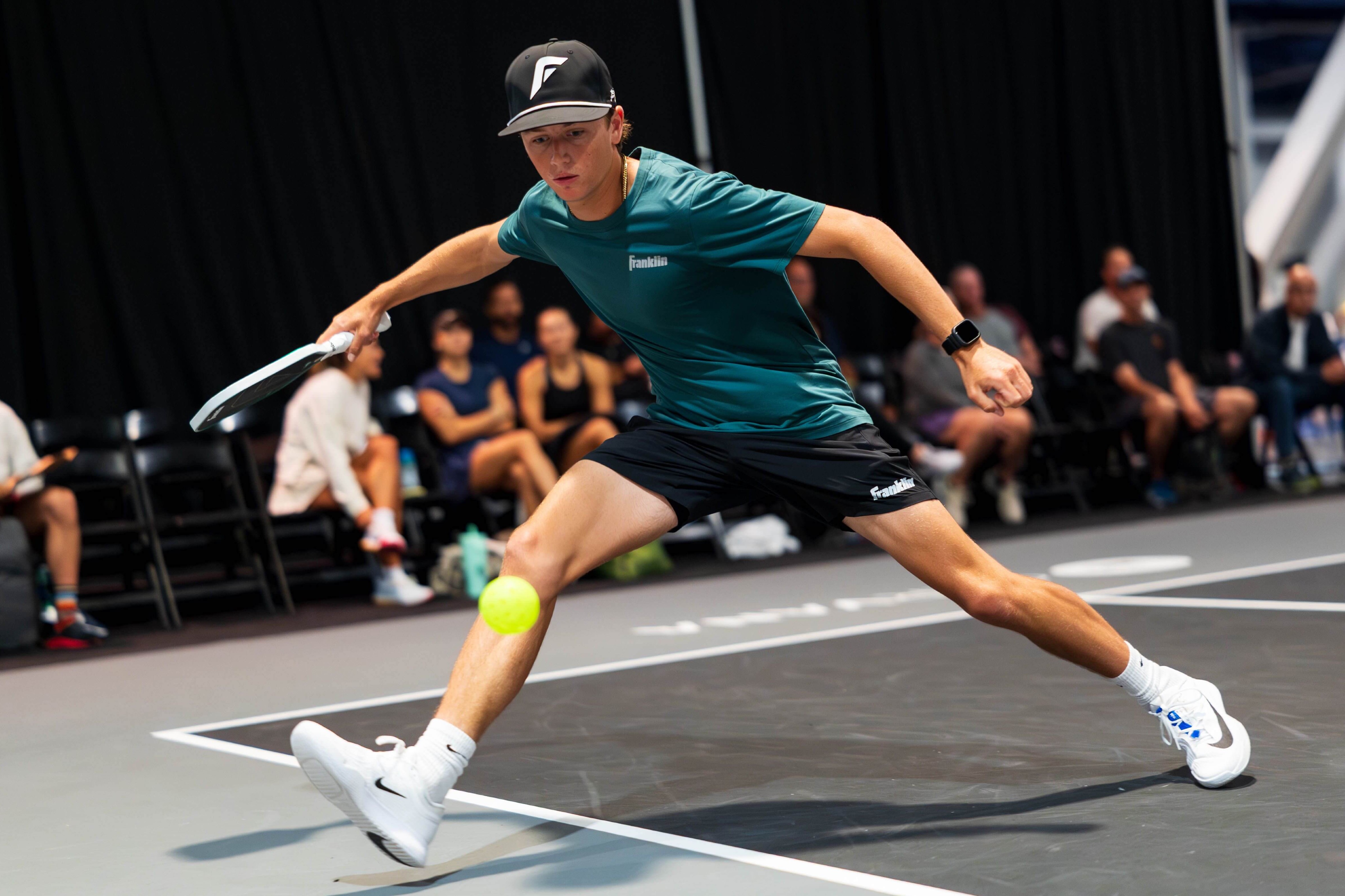 Patriquin in a dark blue shirt, black shorts, white shoes