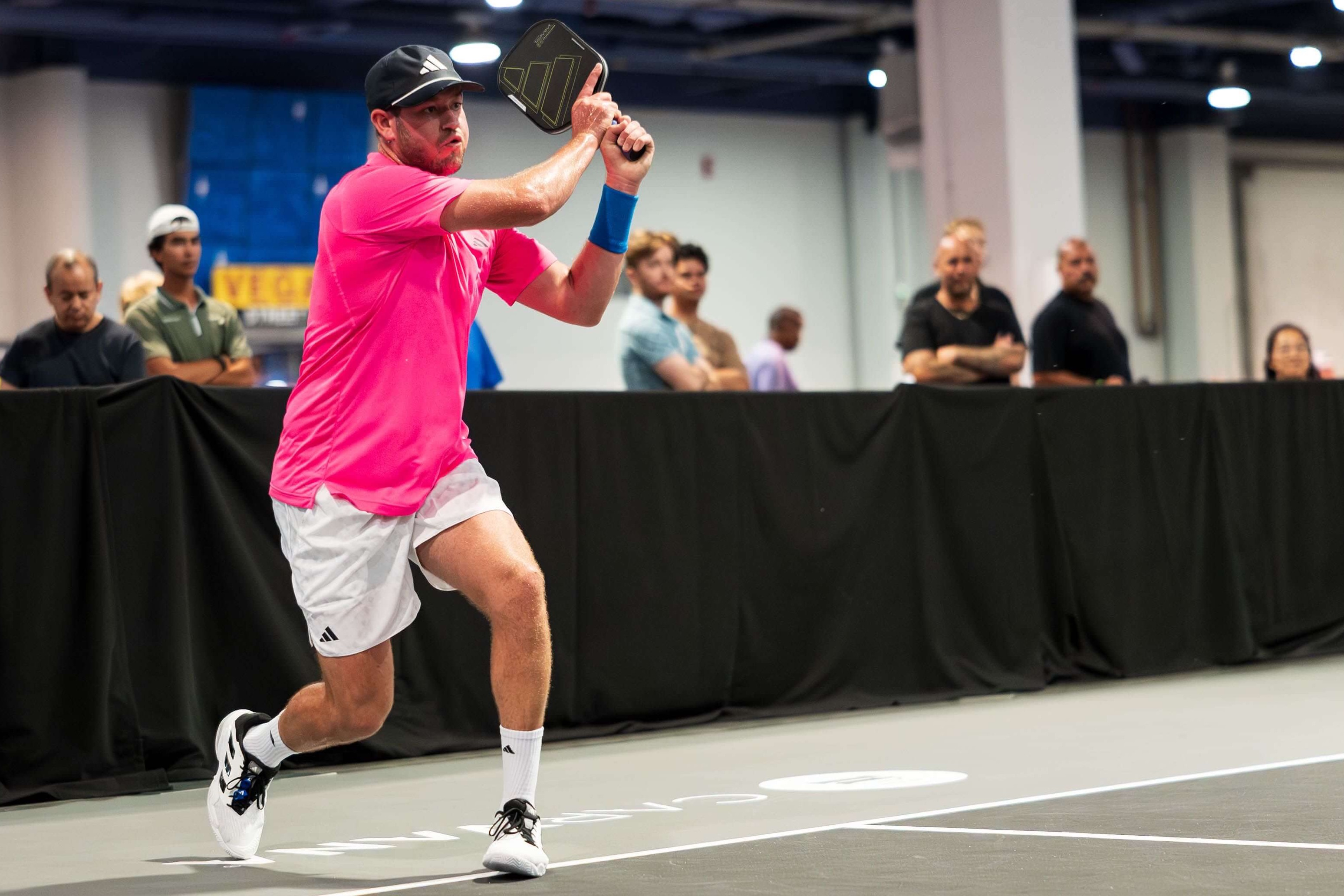 Hewett in a neon pink shirt and white shorts and shoes