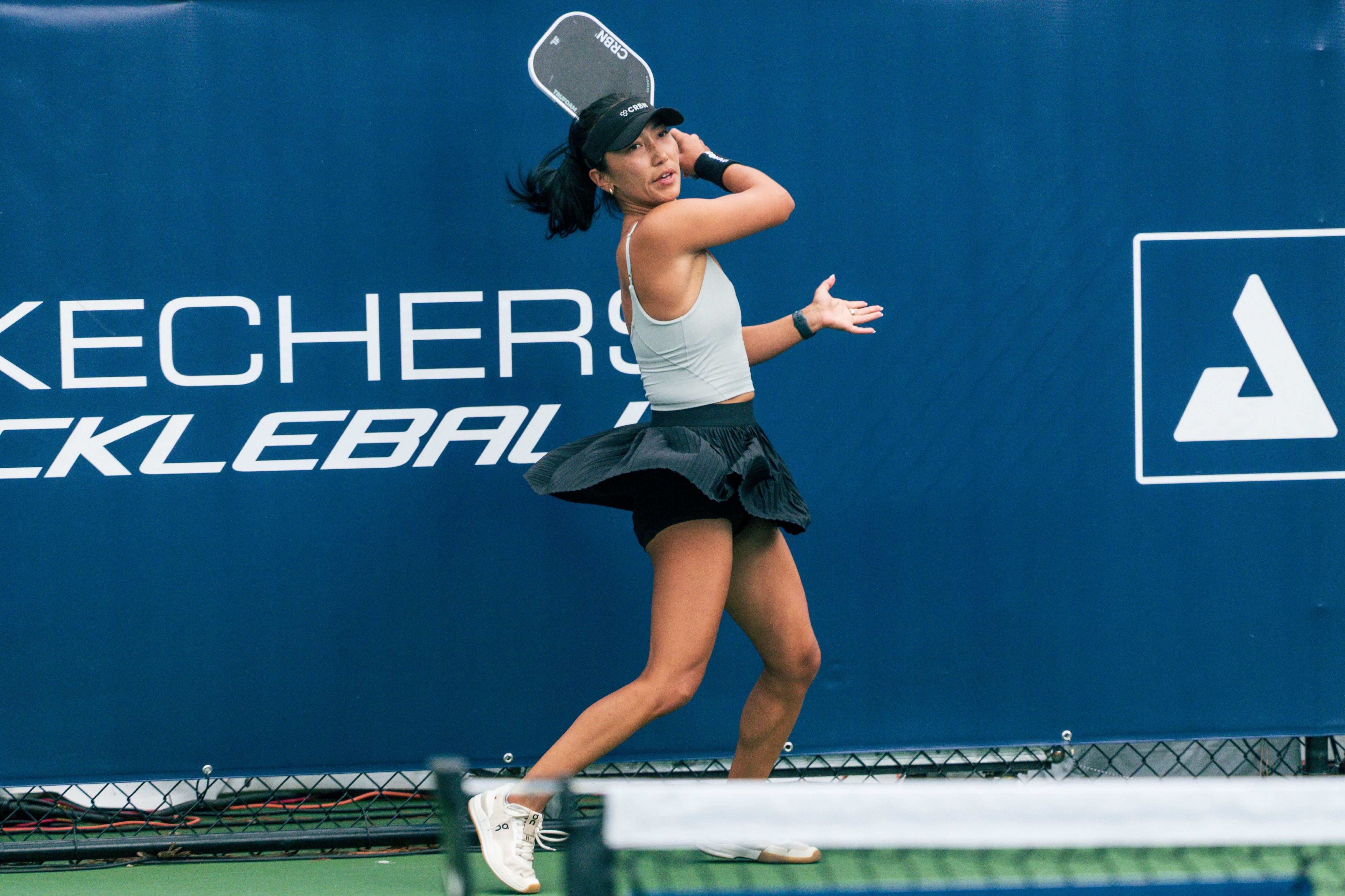 Funaro in fitted green tank top and pleated skirt