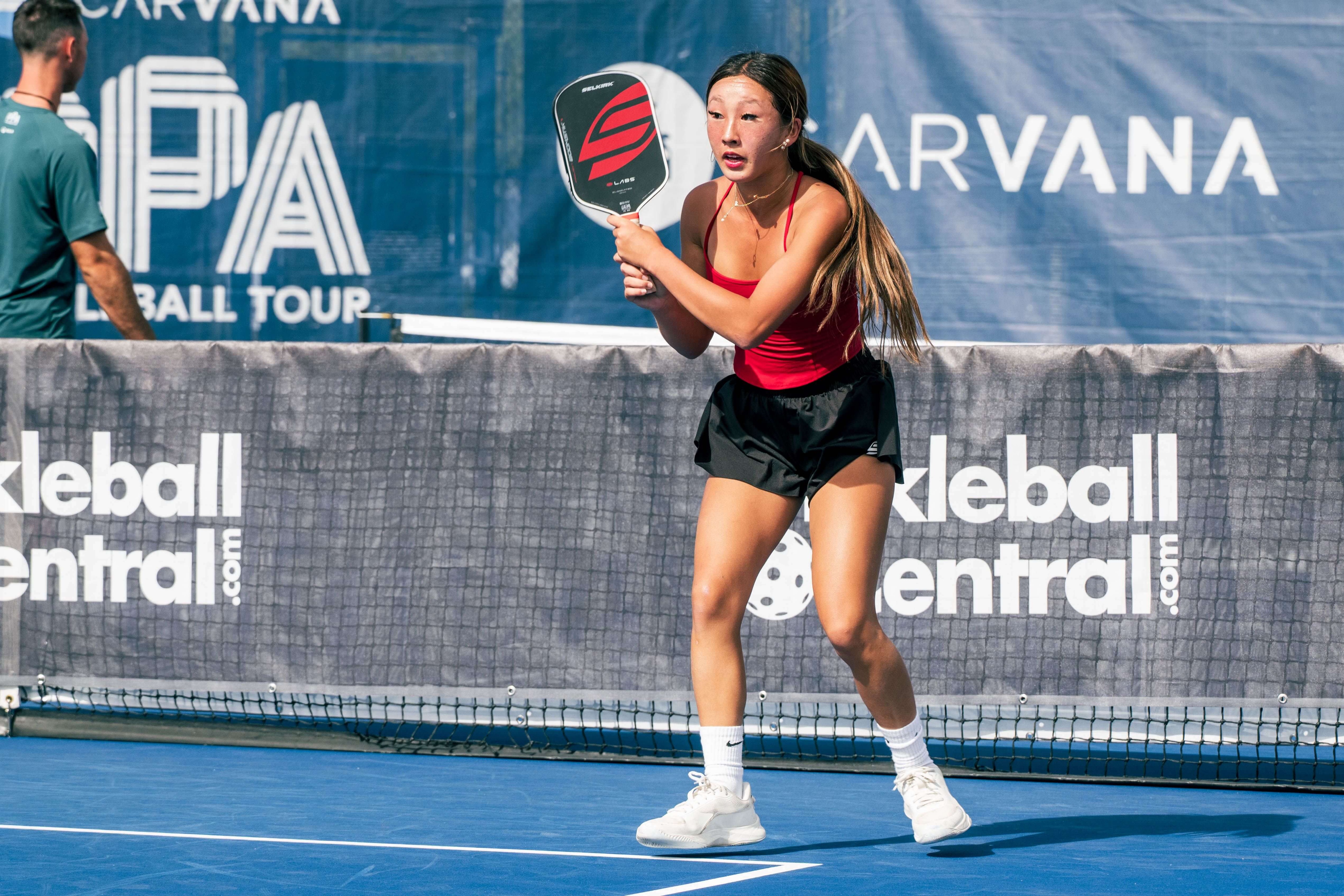 Kunimoto in a red top, black shorts, and white shoes