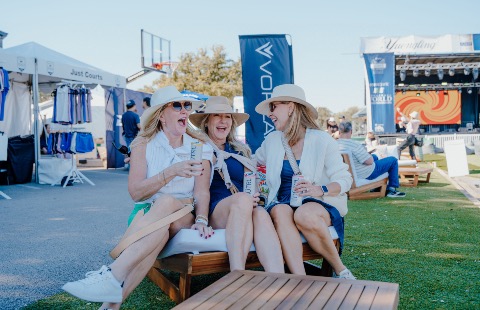 Three women in hats smiling and laughing on Pickleball Boulevard.