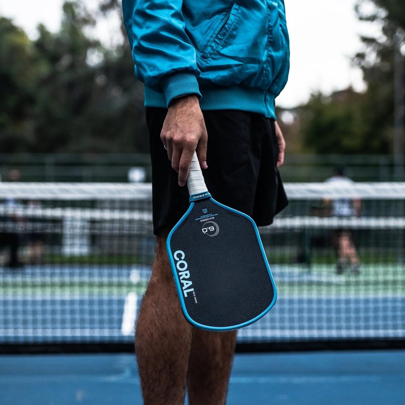 Six Zero Coral Pickleball Paddle in hand on court lifestyle shot